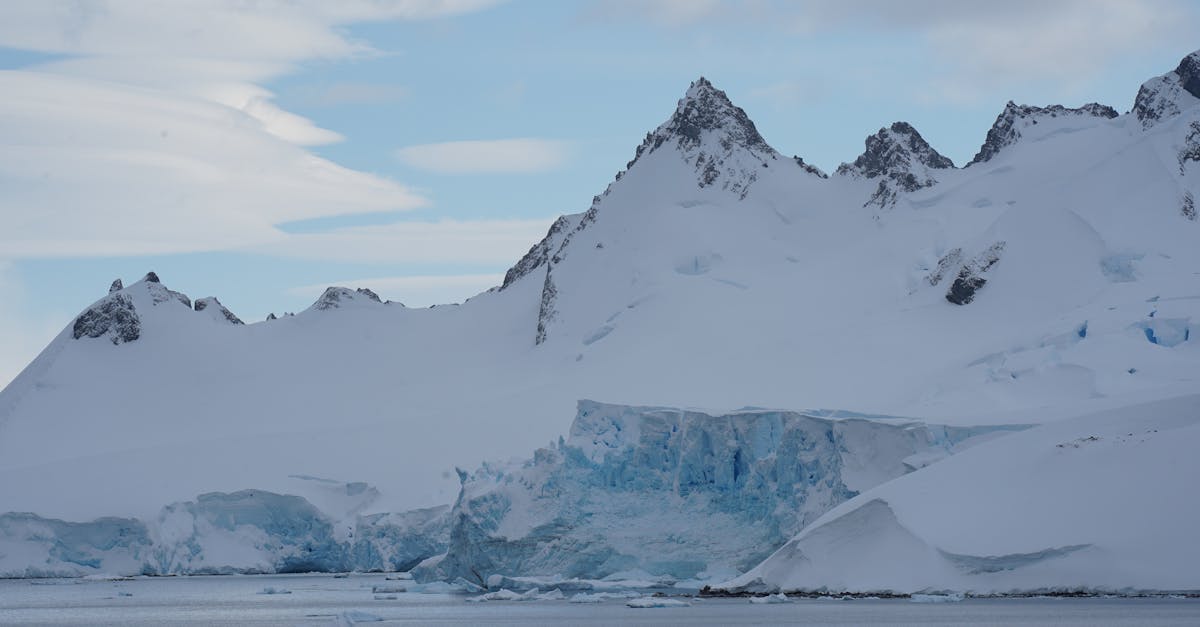 Stunning view of Antarctic glacier with rugged mountain peaks under a clear blue sky.