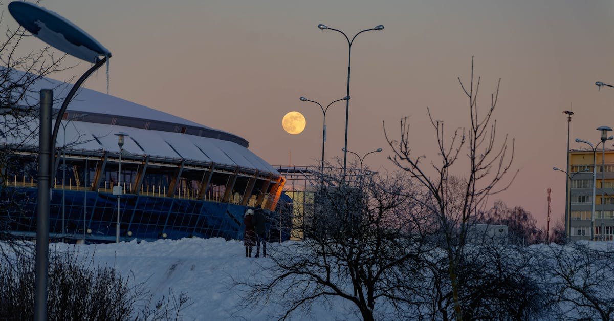 A serene winter scene in Minsk featuring a full moon over snowy landscapes and modern architecture.
