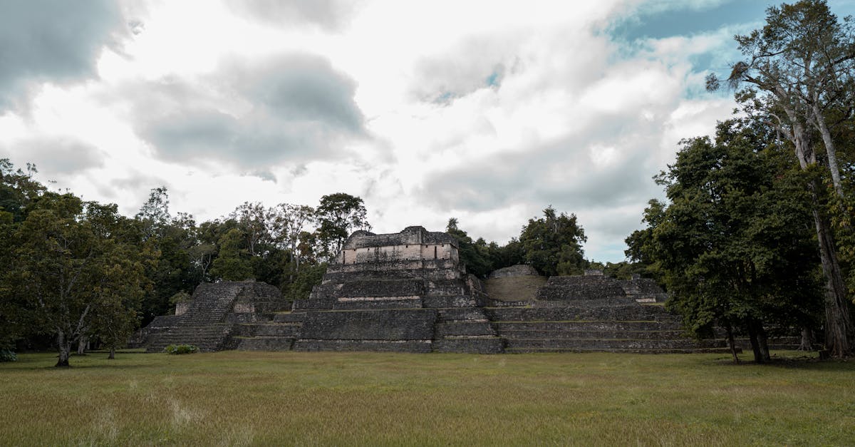 Explore the Caracol Pyramid, an ancient Mayan ruin nestled in lush greenery and under a vast, cloudy sky.