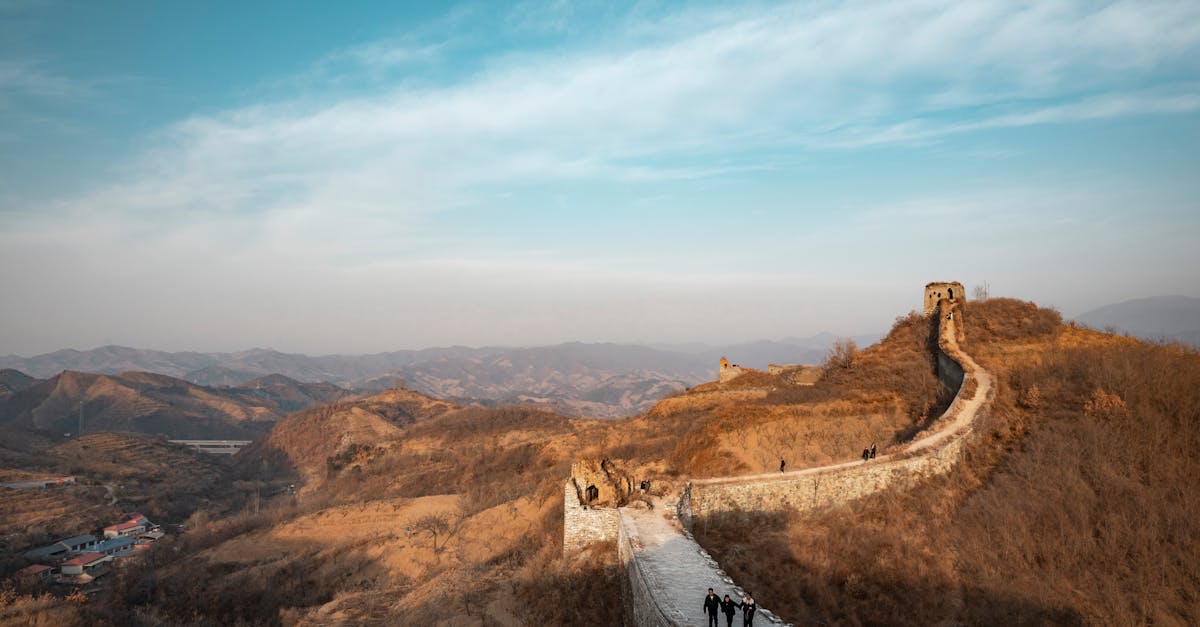 A scenic view of the Great Wall of China stretching across the rugged landscape under a clear blue sky.