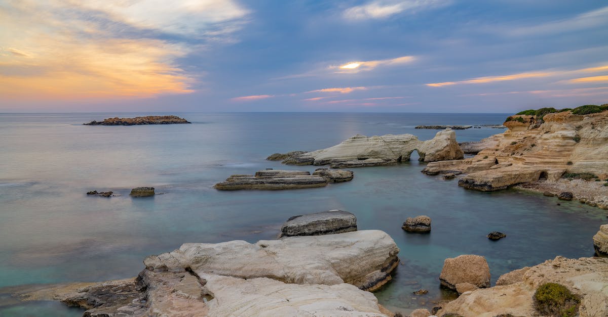 Peaceful sunset over a rocky coastline with ocean view in Cyprus. Ideal for travel and nature themes.