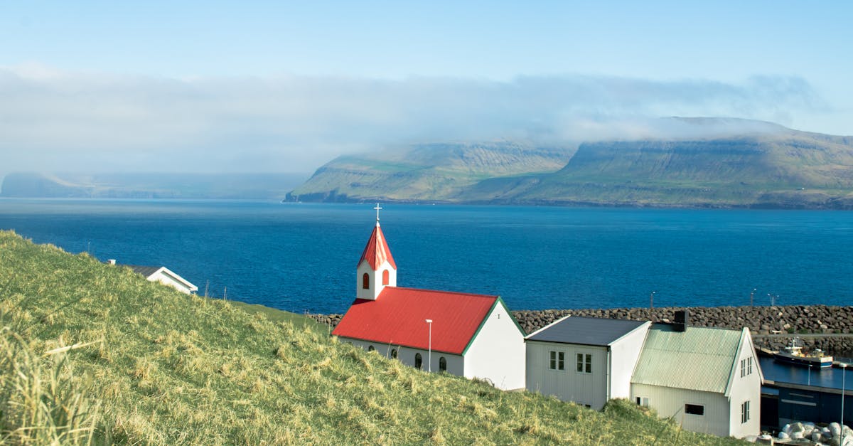 Idyllic coastal village view in Faroe Islands with traditional church and ocean backdrop.