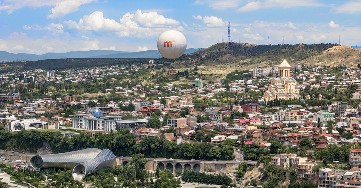 A breathtaking aerial photograph of Tbilisi featuring iconic landmarks and lush surroundings.
