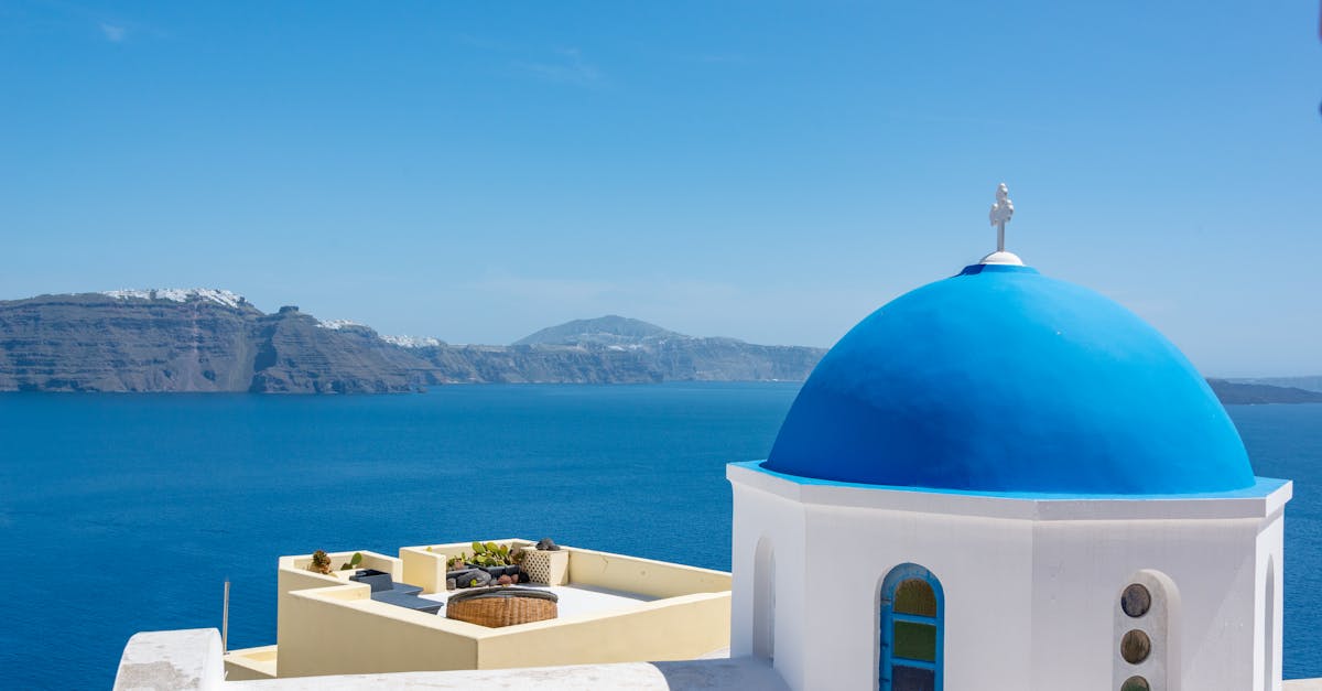 Iconic blue dome church in Santorini with a stunning view of the Aegean Sea.