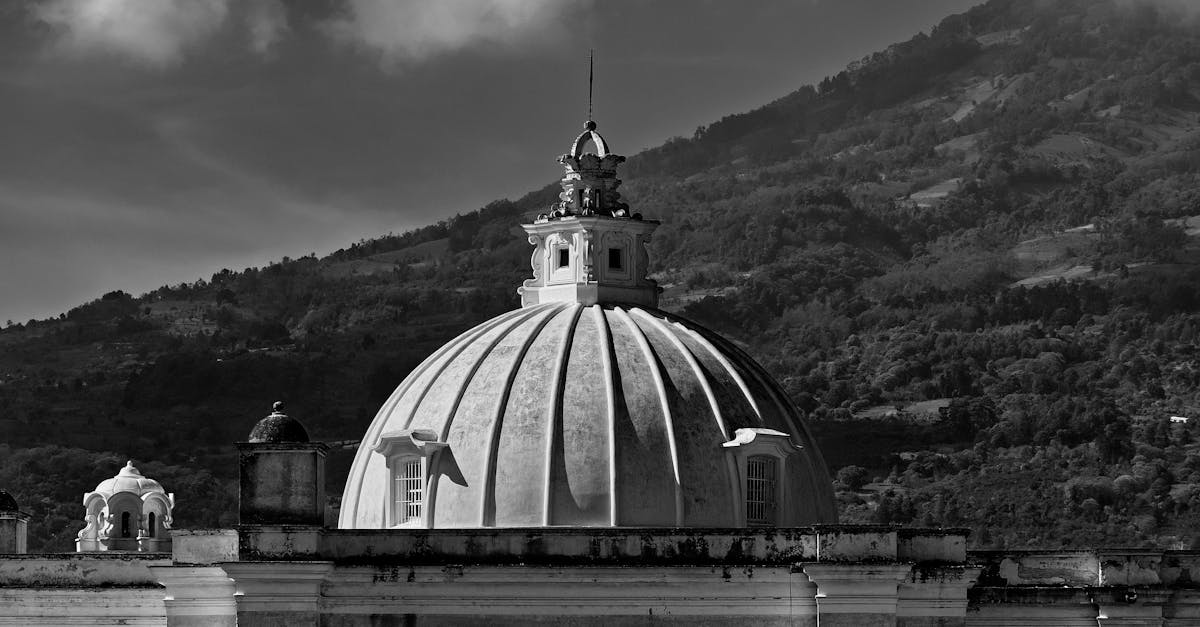 Grayscale photo of a historic dome with a scenic mountain backdrop in Antigua, Guatemala.