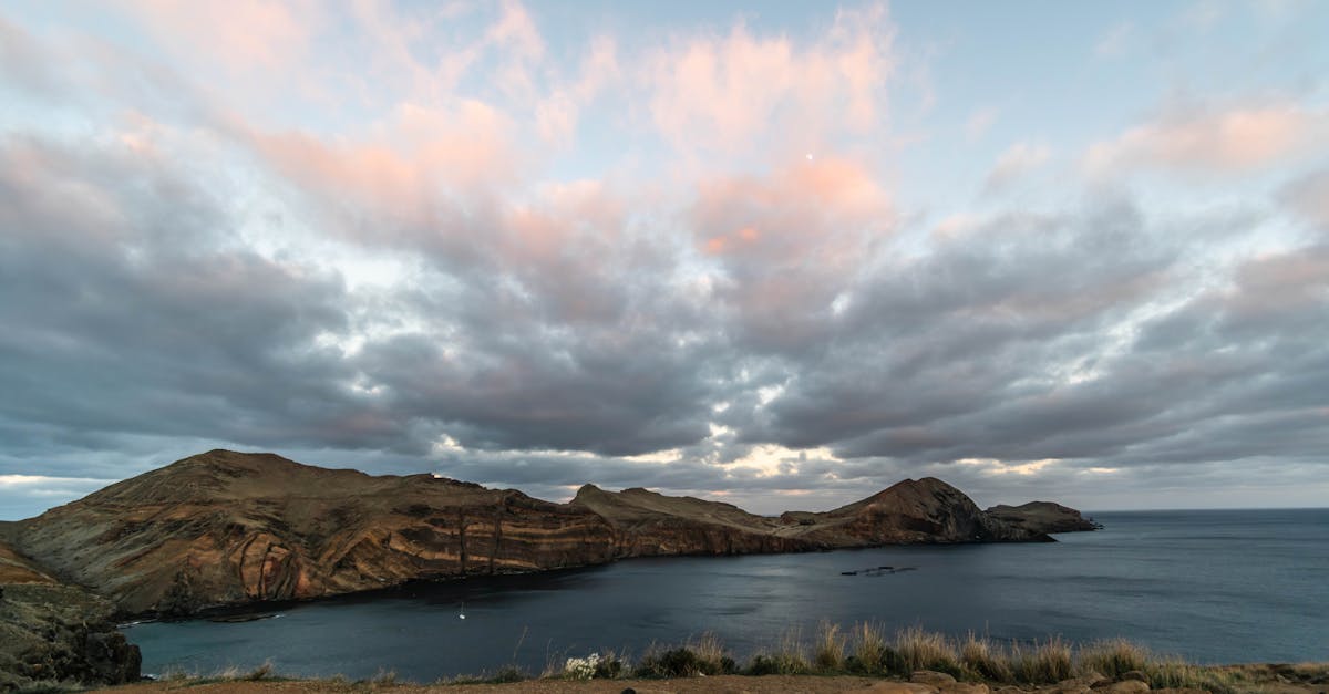Scenic view of Porto Santo Island, Madeira at sunset with dramatic clouds and rocky coastline.
