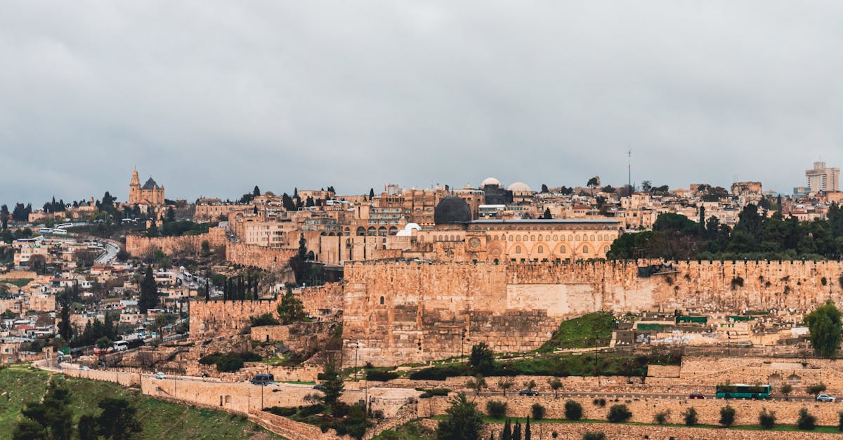 View of Jerusalem showcasing the ancient city walls and iconic architecture under a cloudy sky.
