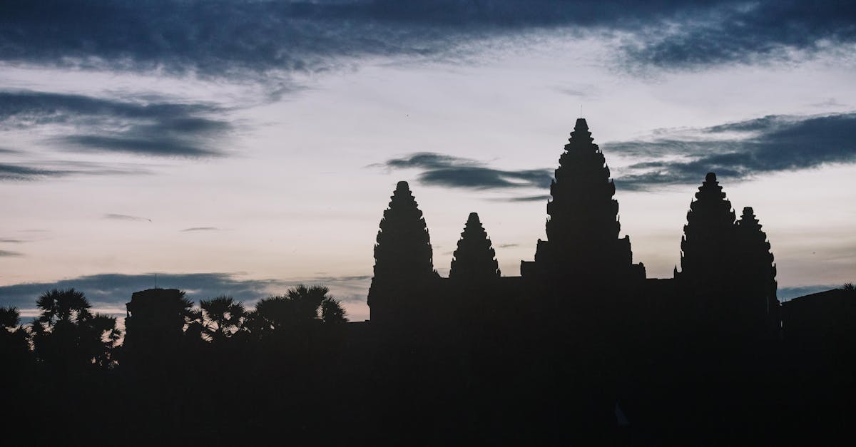 Silhouette of Angkor Wat temple at dusk with dramatic sky.