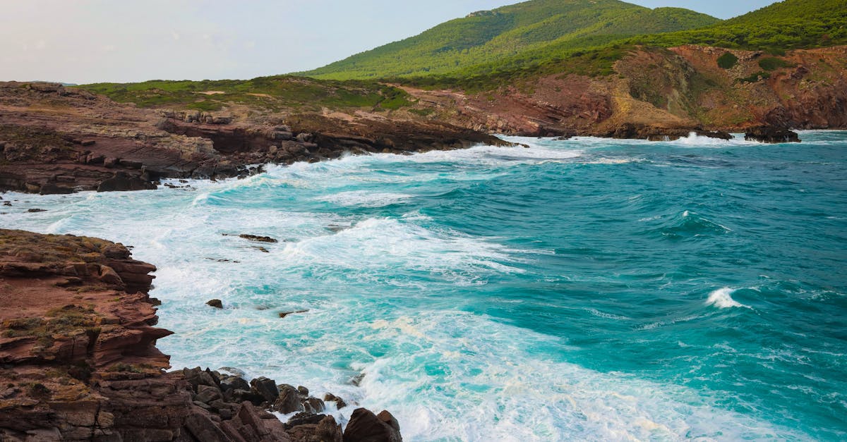 Stunning view of Alghero coastline with rocky cliffs and turquoise waves crashing.