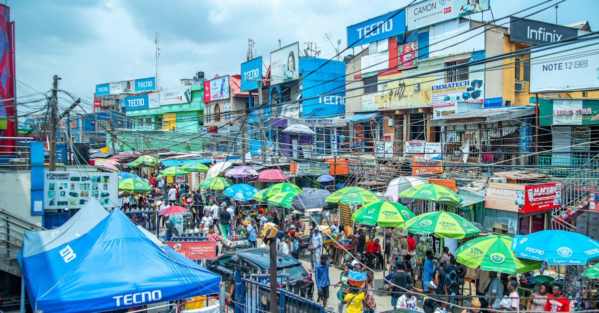 A bustling market with colorful umbrellas and billboards in Lagos, Nigeria.