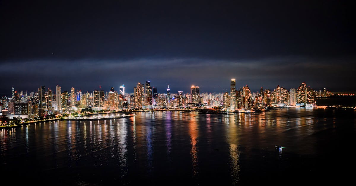 Nighttime aerial view of Panama City's illuminated skyline reflecting on the water.
