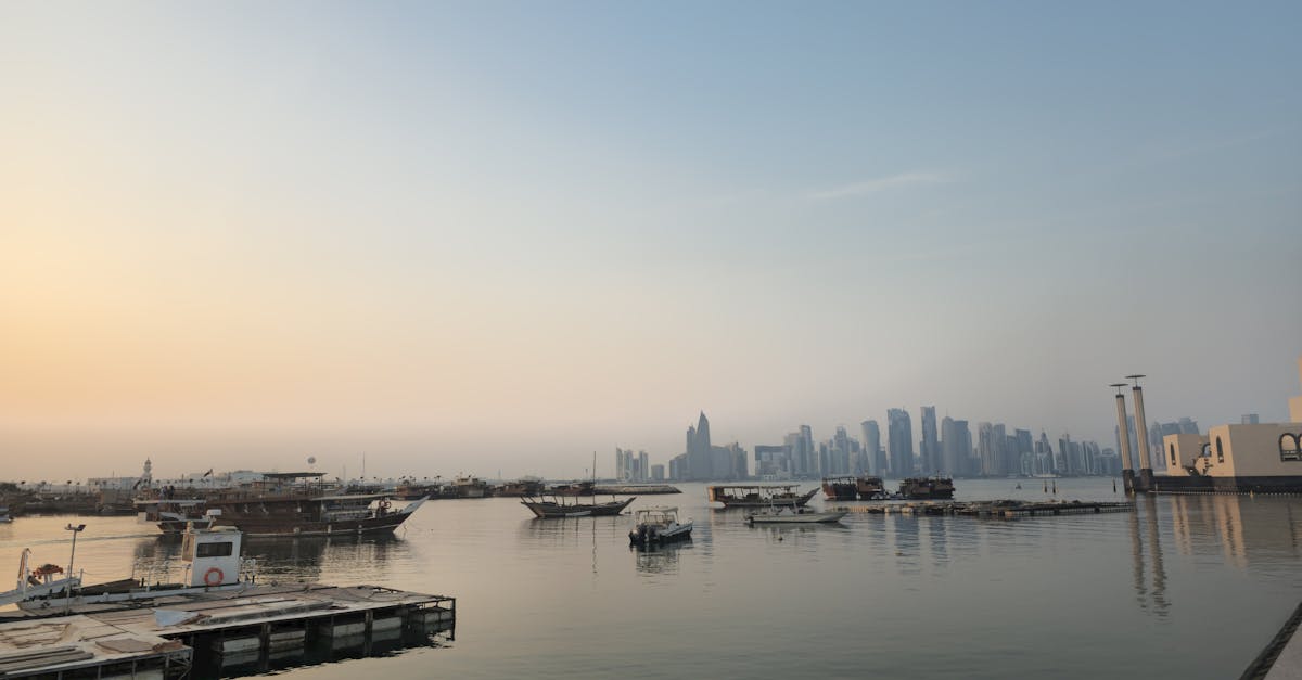 Doha skyline viewed from waterfront with boats at sunrise, showcasing Qatar's blend of tradition and modernity.