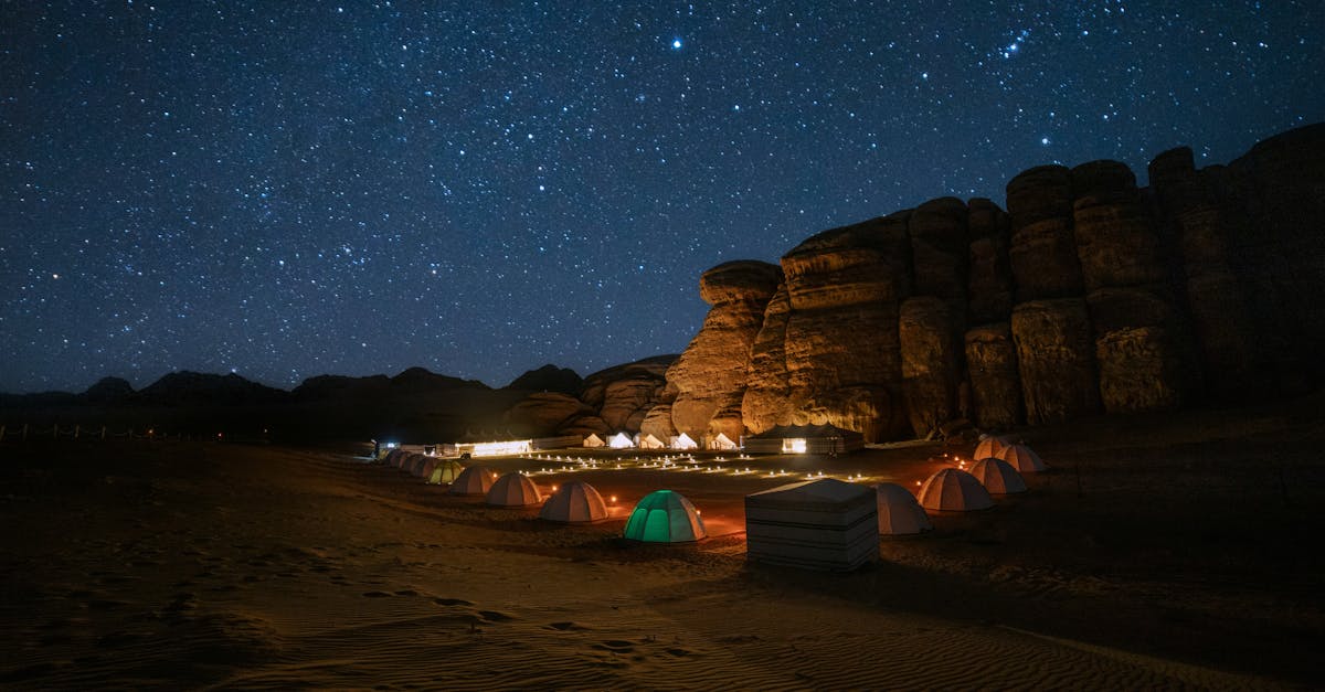 Breathtaking view of a starry night sky over a desert campsite in Tabuk, Saudi Arabia, with dramatic rock formations.