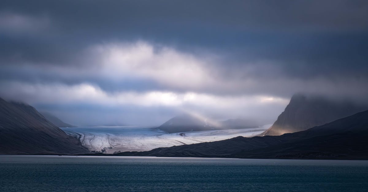 A captivating view of a glacier under dramatic clouds in Svalbard, showcasing nature's raw beauty.