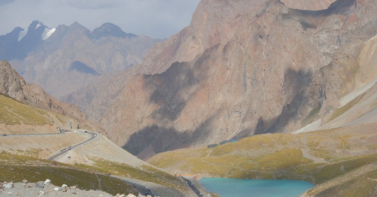 Scenic view of a mountain road with a stunning turquoise alpine lake and rocky terrain.