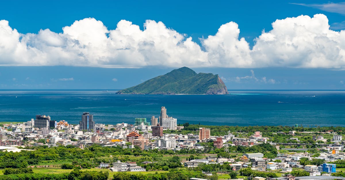Aerial view of a vibrant Taiwanese cityscape with lush greenery and a striking island in the background.