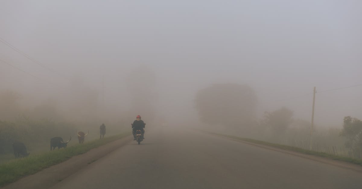 A lone motorcycle travels on a misty road in Kabale, Uganda, surrounded by fog.