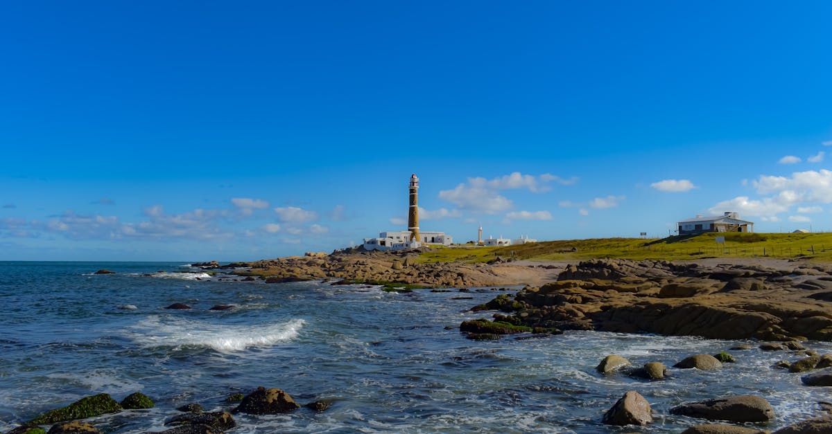 Scenic view of Cabo Polonio lighthouse with rocky coastline under a clear blue sky in Uruguay.