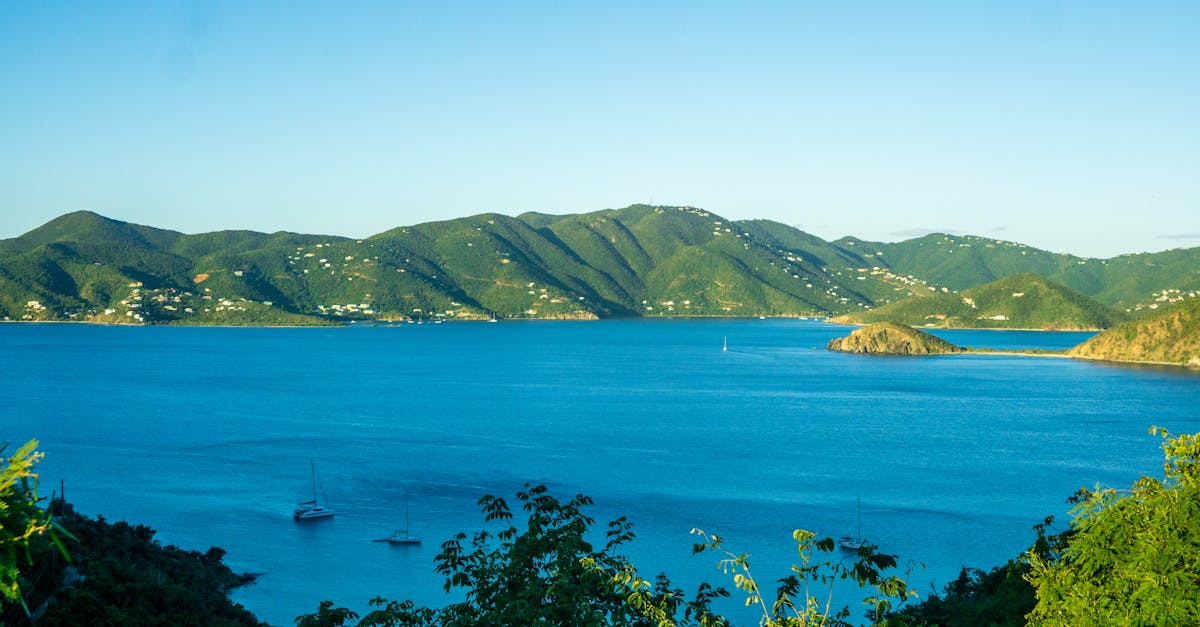 Scenic view of the Caribbean Sea with sailboats and lush mountains under clear blue skies.